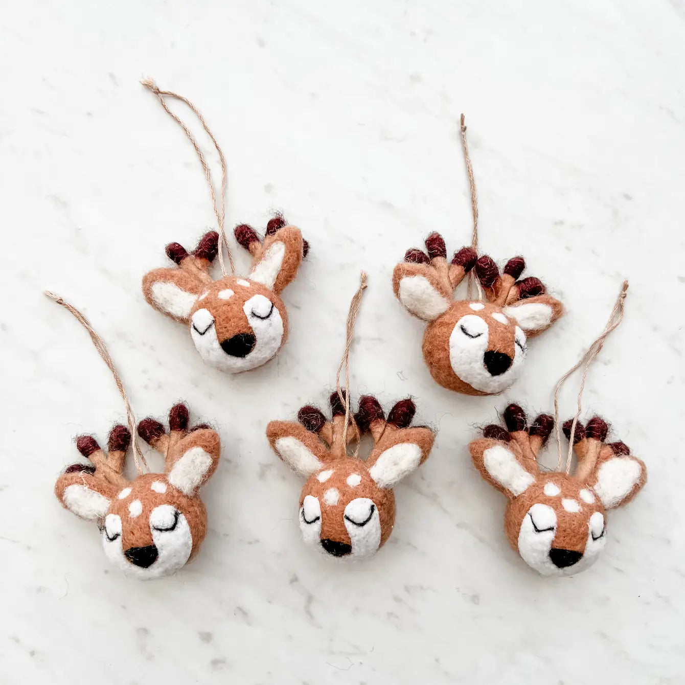 A set of five brown and white felt reindeer ornaments with black antlers, attached with strings for hanging.