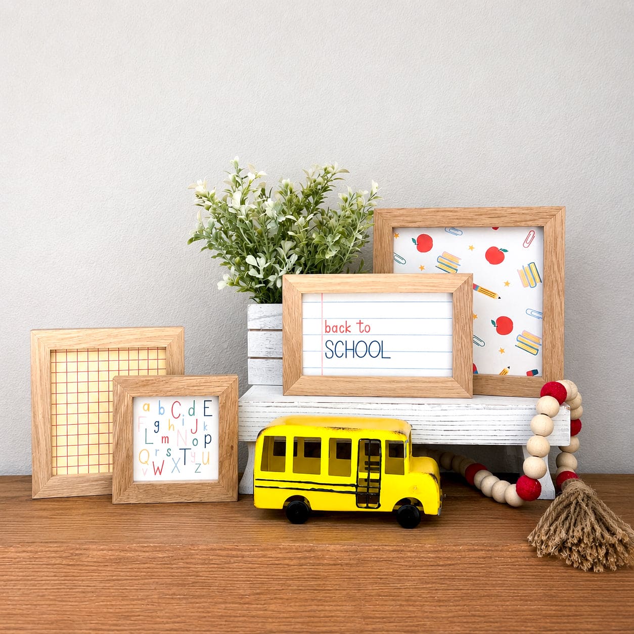 Metal yellow school bus decor for shelf, tabletop, classroom, and back to school decorating with four back to school signs in wood frames on a wooden shelf.