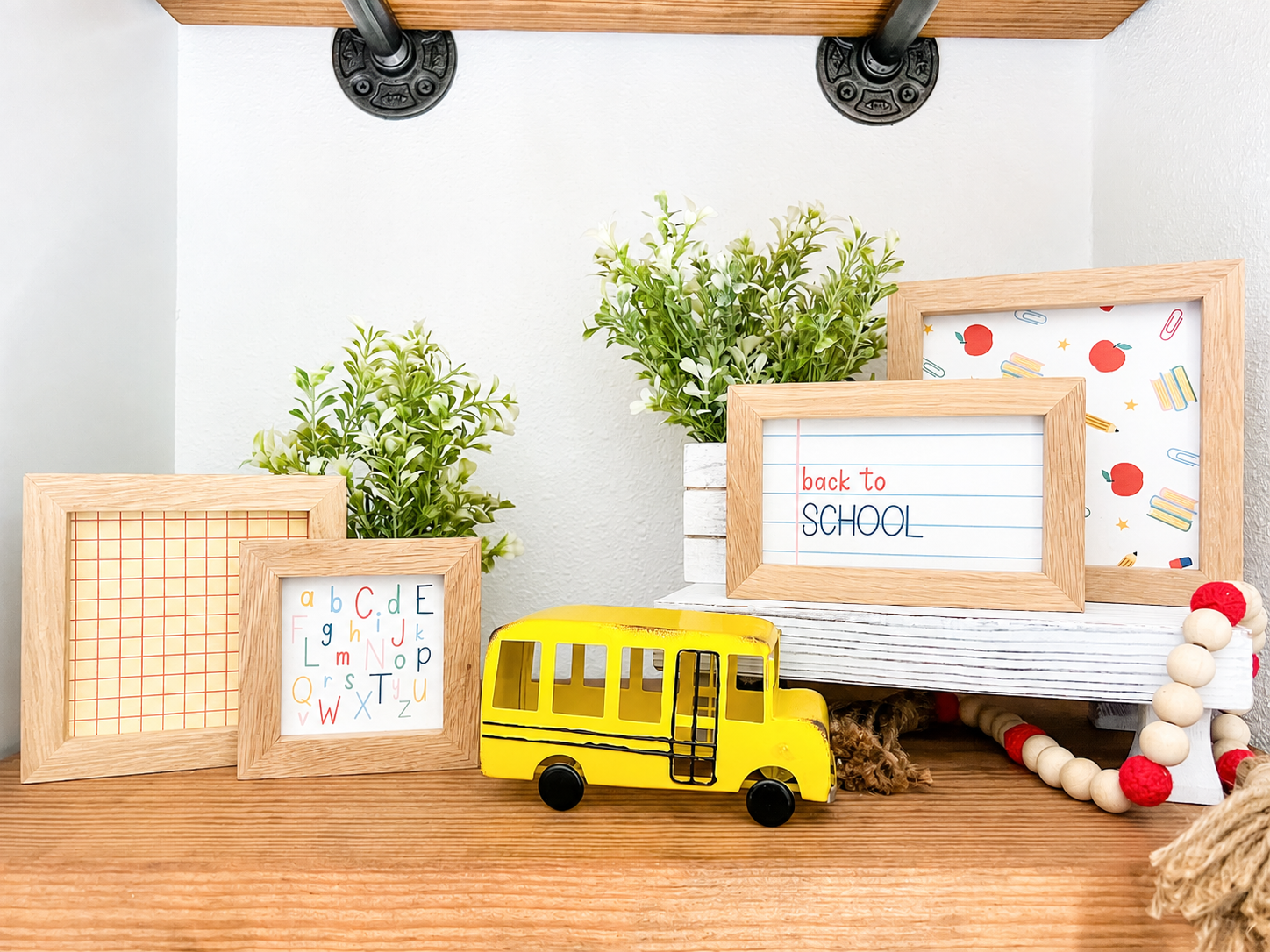 Metal yellow school bus decor for shelf, tabletop, classroom, and back to school decorating with four back to school signs in wood frames on a wooden shelf.