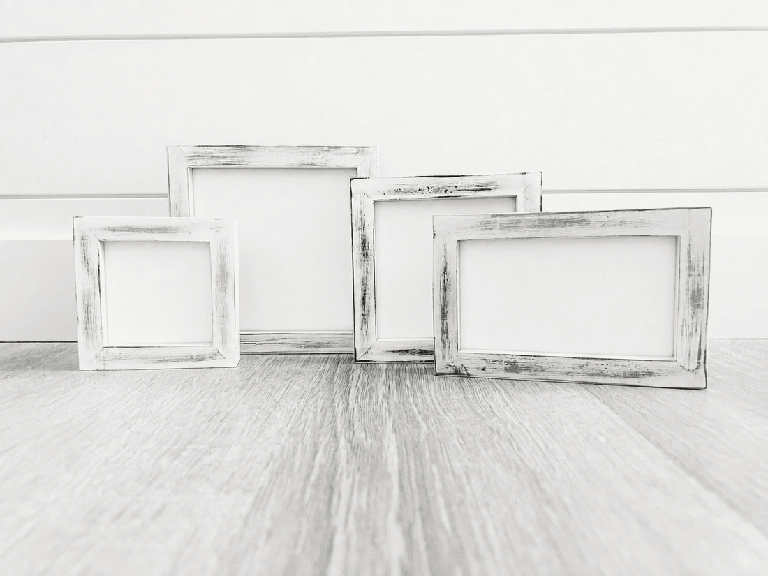Four distressed white picture frames in different sizes arranged in a 2x2 grid on a white marble surface. White distressed pine frame for tiered tray, shelf decor, seasonal inserts and photos