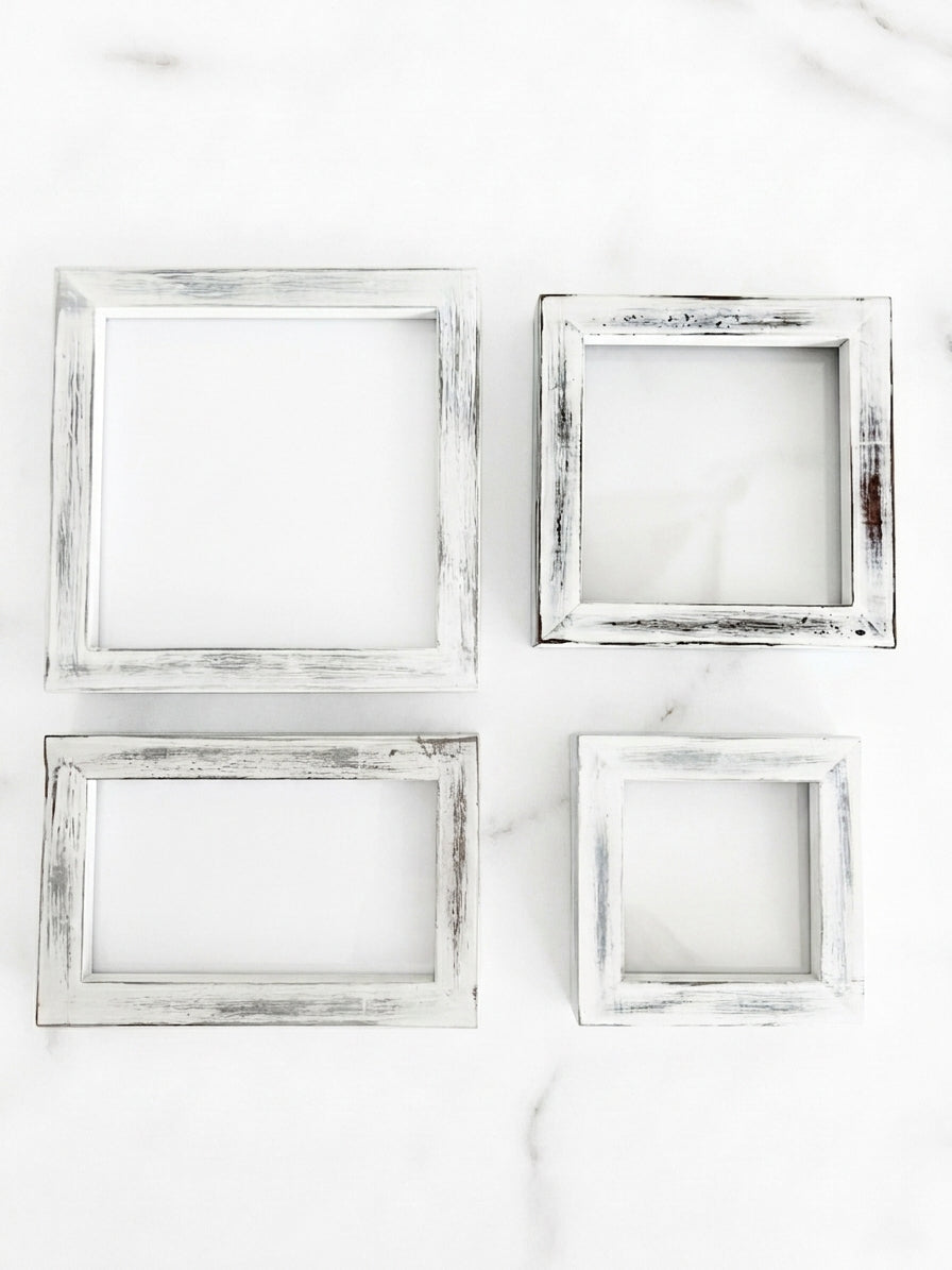 Four distressed white picture frames in different sizes arranged in a 2x2 grid on a white marble surface. White distressed pine frame for tiered tray, shelf decor, seasonal inserts and photos