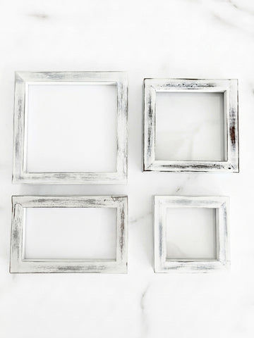 Four distressed white picture frames in different sizes arranged in a 2x2 grid on a white marble surface. White distressed pine frame for tiered tray, shelf decor, seasonal inserts and photos