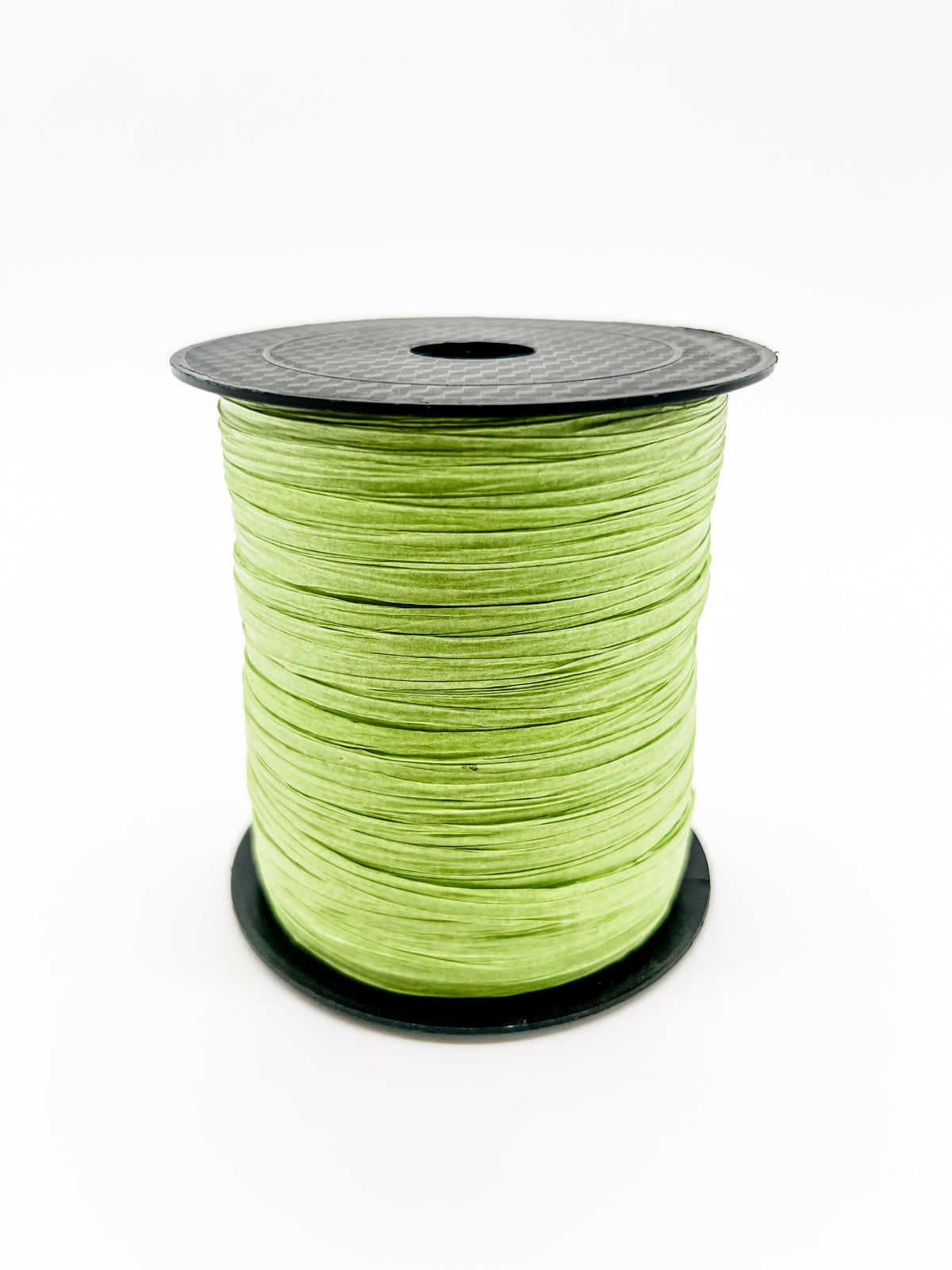 A spool of lime green paper raffia with a black plastic top and base, photographed on a clean white background.
