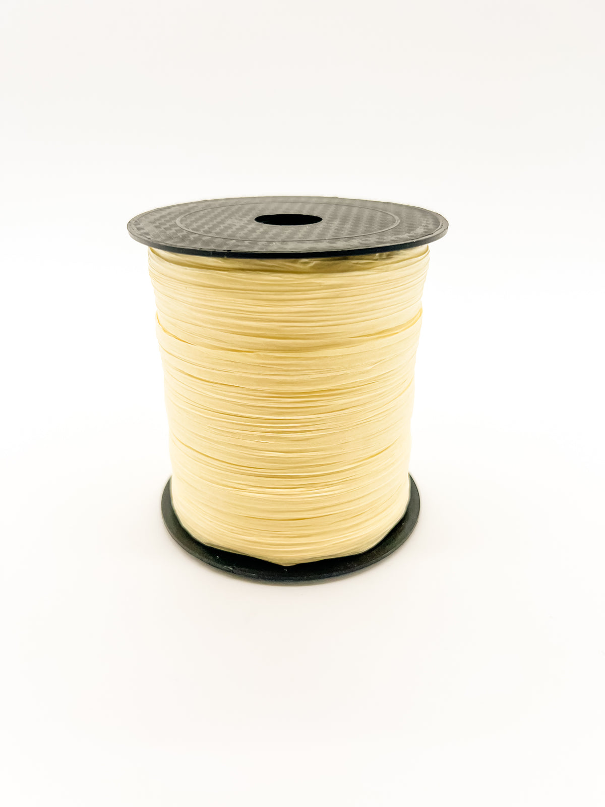 A spool of light yellow paper raffia with a black plastic top and base, photographed on a clean white background.