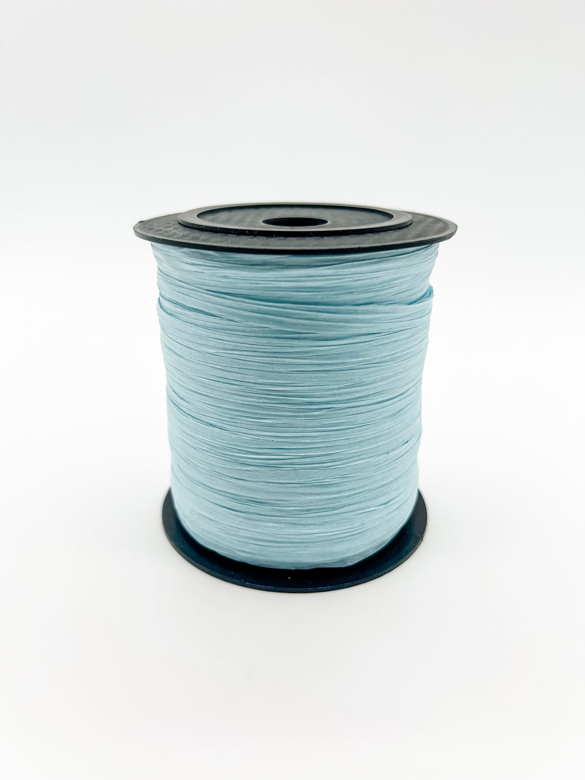 A spool of baby blue paper raffia with a black plastic top and base, photographed on a clean white background.