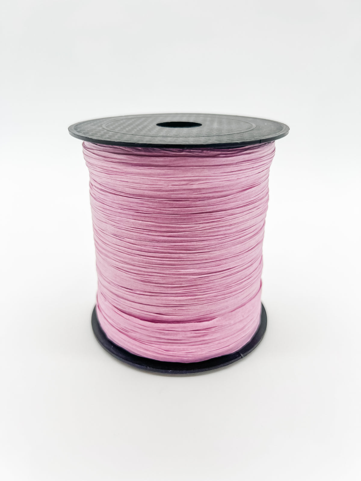 A spool of lilac paper raffia with a black plastic top and base, photographed on a clean white background.