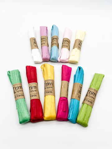 11 rolled skeins of paper raffia including red, green, blue, yellow and more.