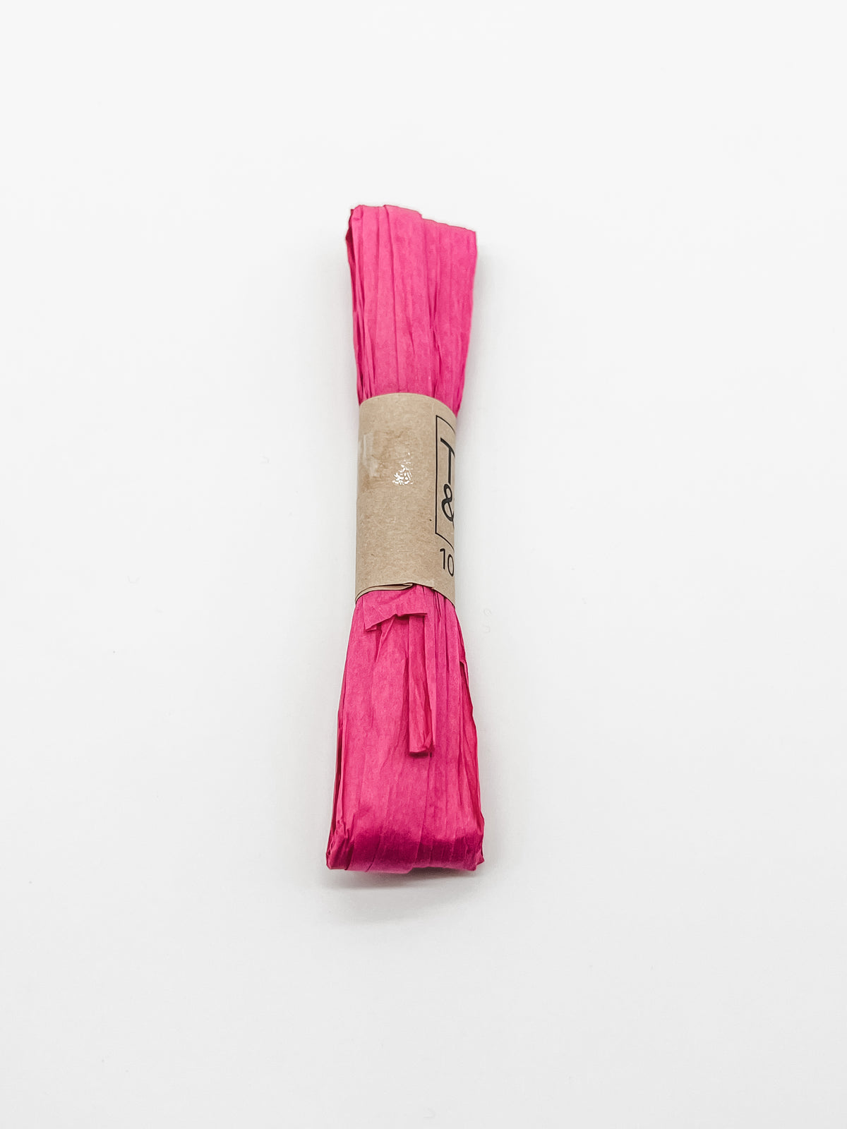 A roll of raspberry pink raffia wrapped with a brown paper band that reads 'Trim & Twine' and '10 Yards', photographed on a plain white background.