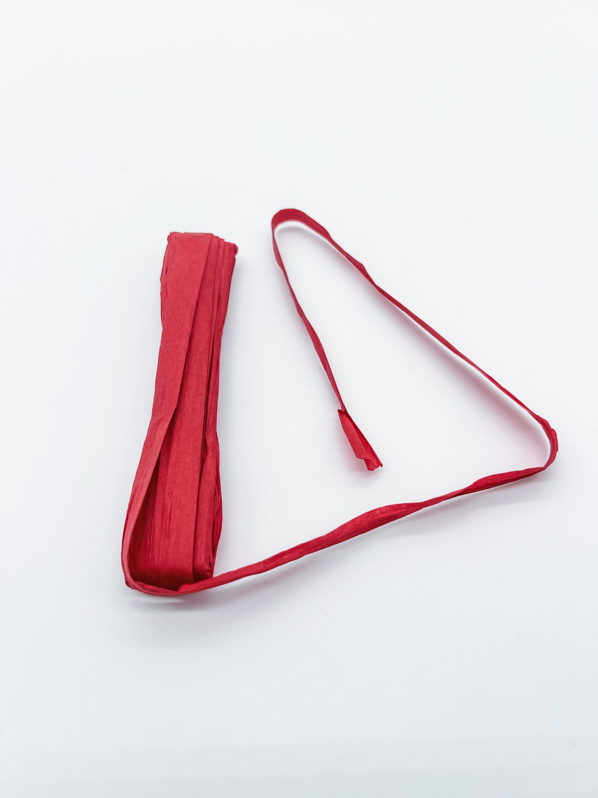 A roll of red raffia unwrapped to show the product, photographed on a plain white background.