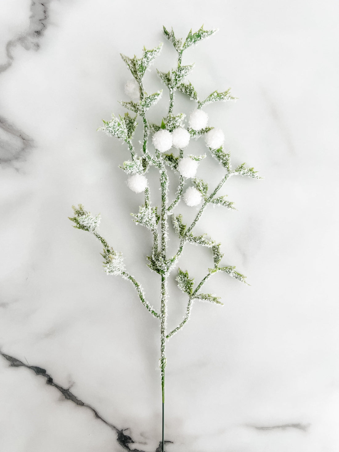 Set of decorative branches with small white berries on a marble surface