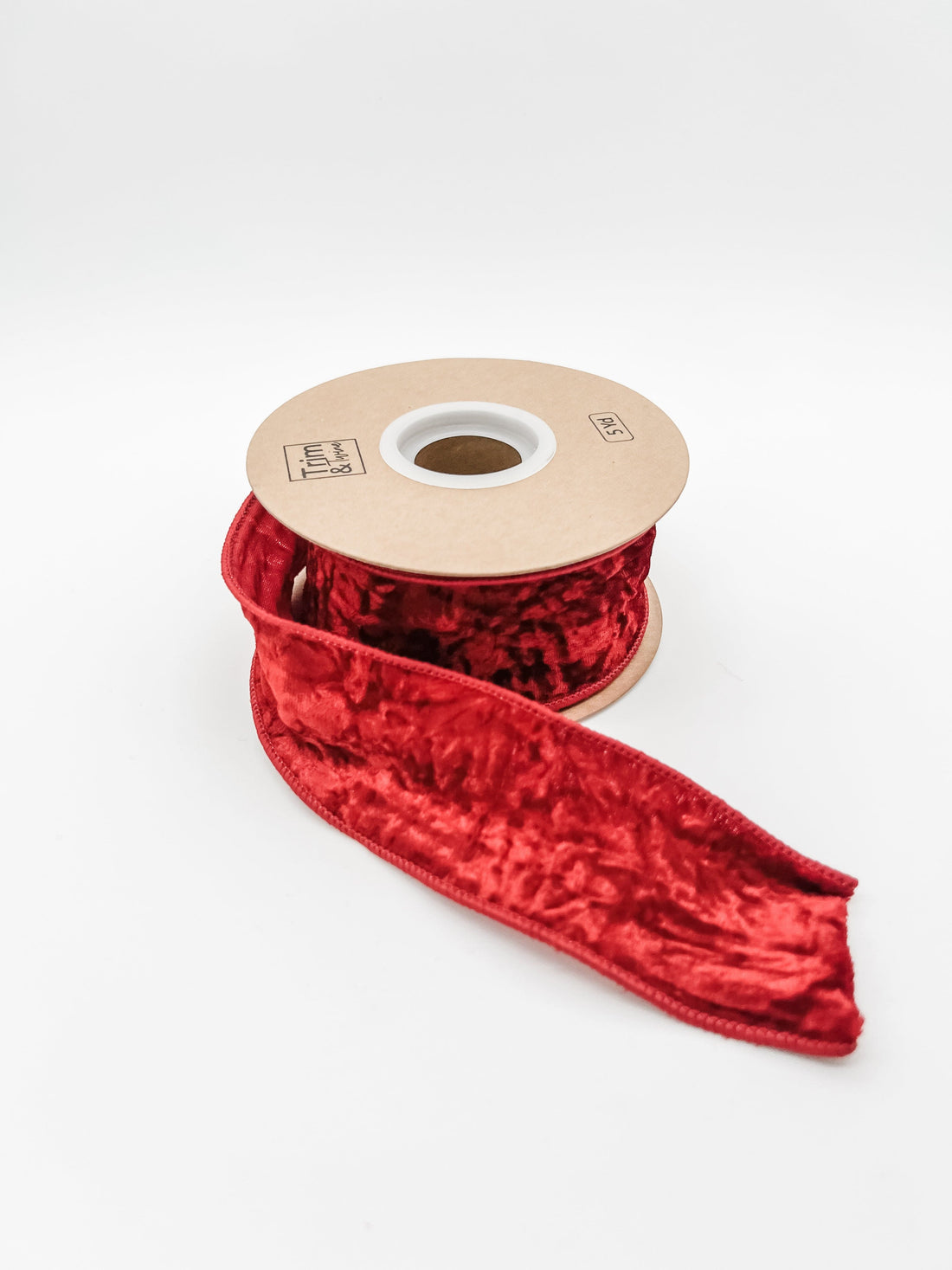 Red crushed velvet ribbon on a spool against a white background