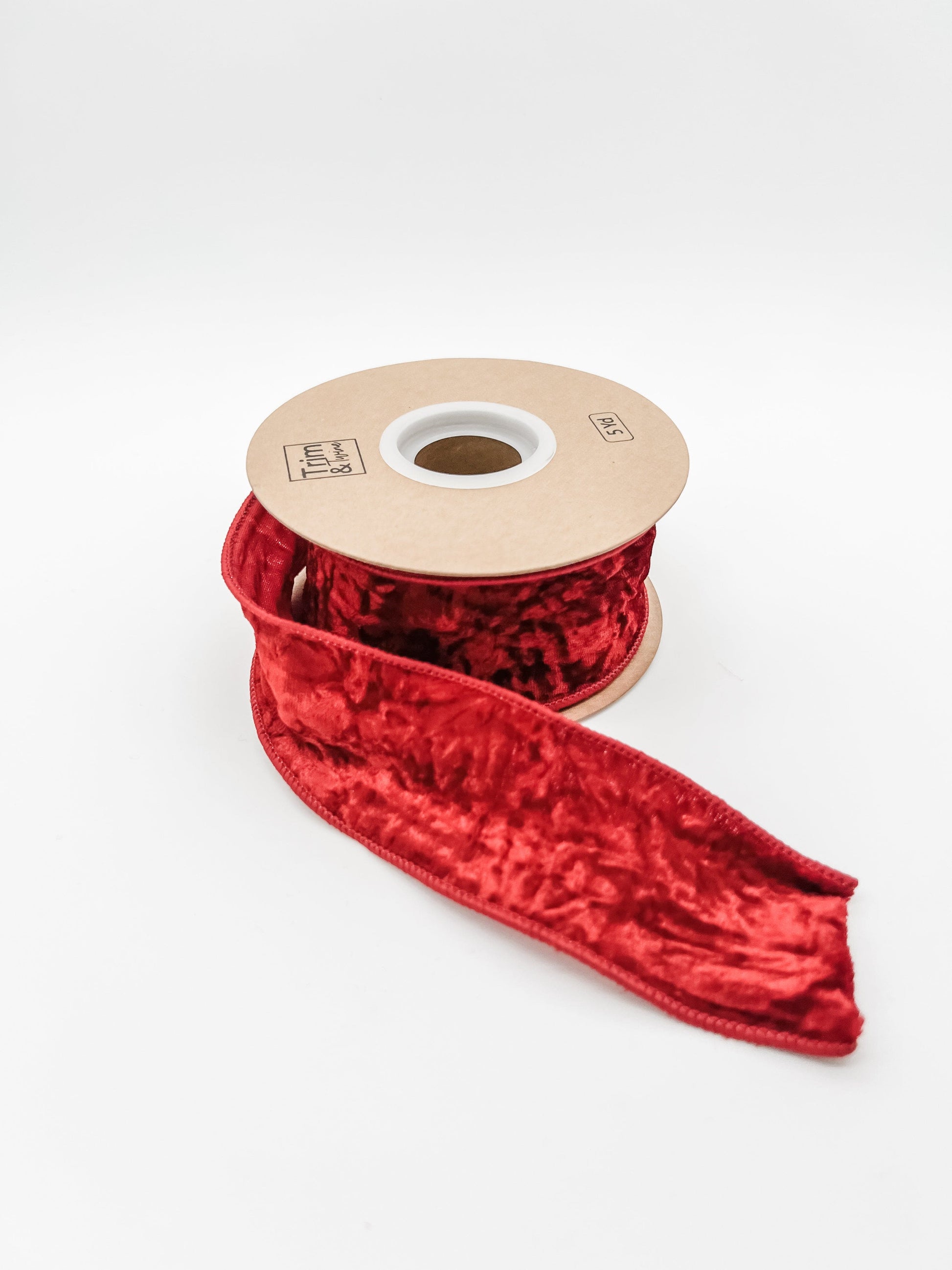 Red crushed velvet ribbon on a spool against a white background