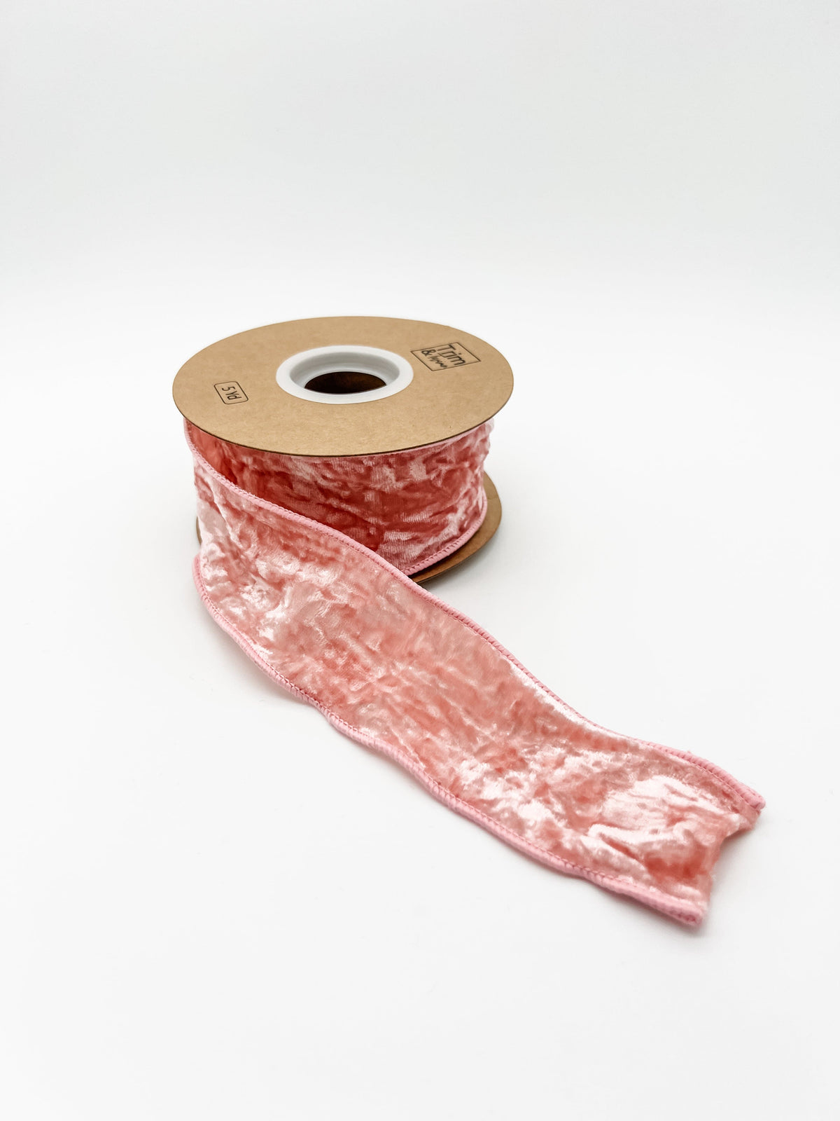 Pink crushed velvet ribbon spool on a white background