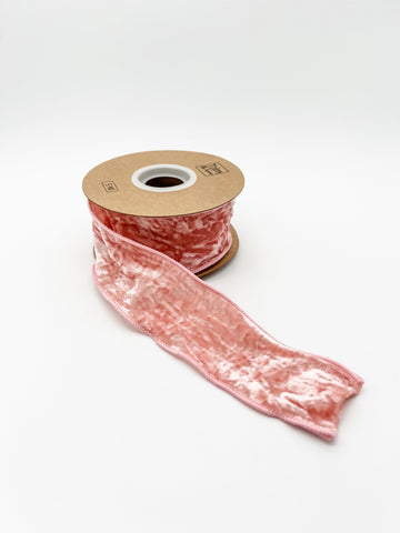 Pink crushed velvet ribbon spool on a white background