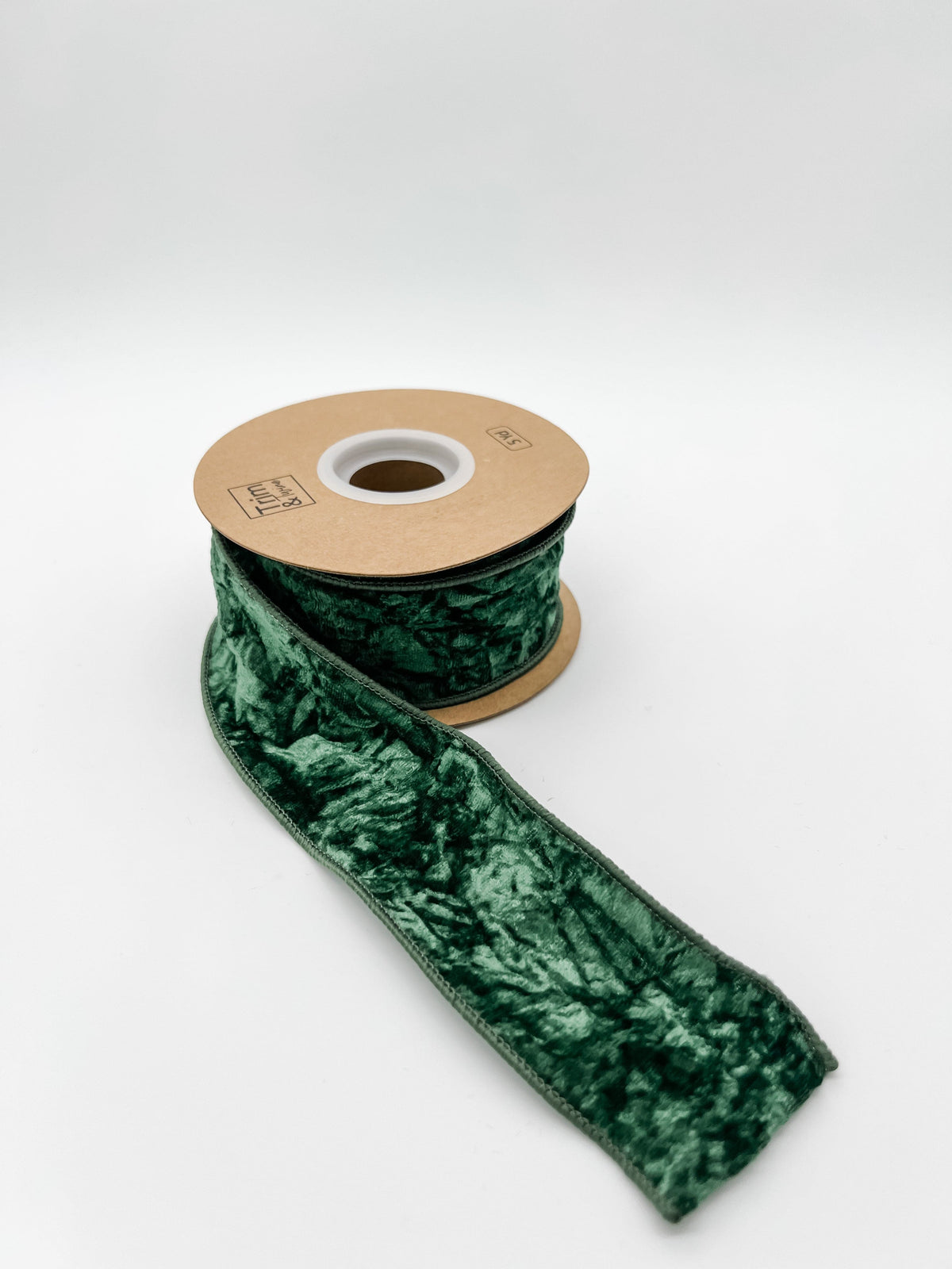 Green crushed velvet ribbon on a spool with a white background