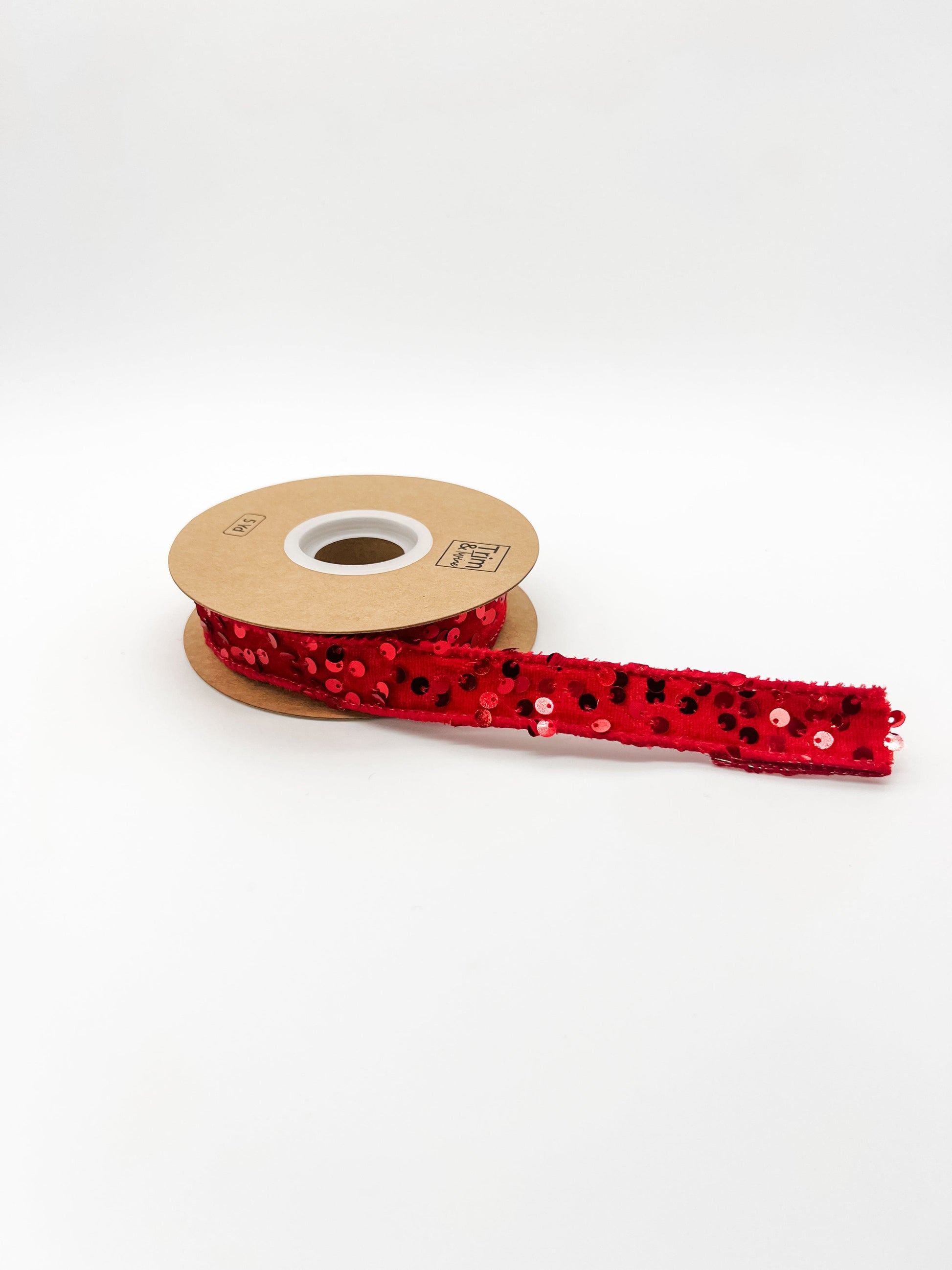 Spool of red sequin ribbon on a white background
