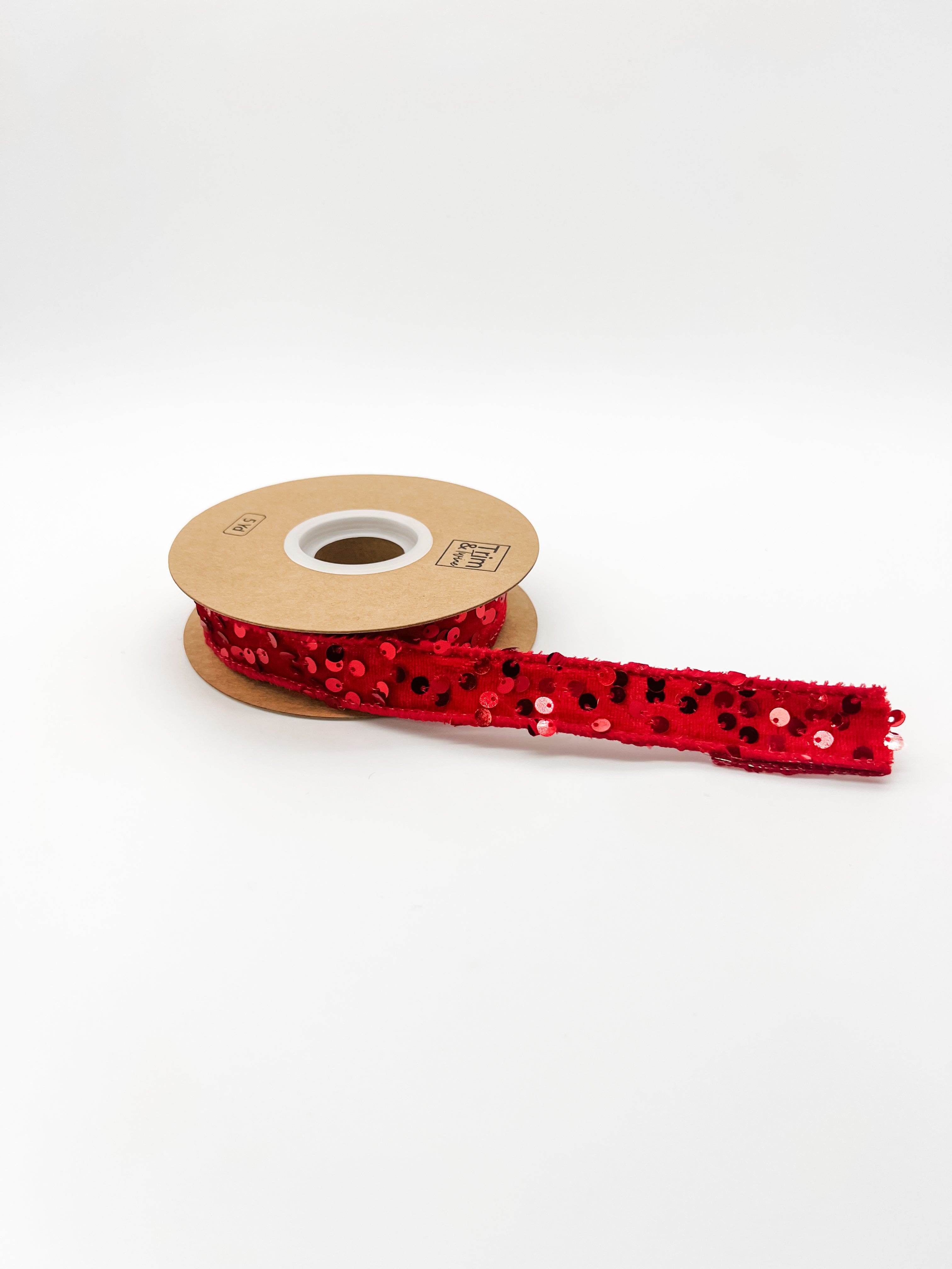 Spool of red sequin ribbon on a white background