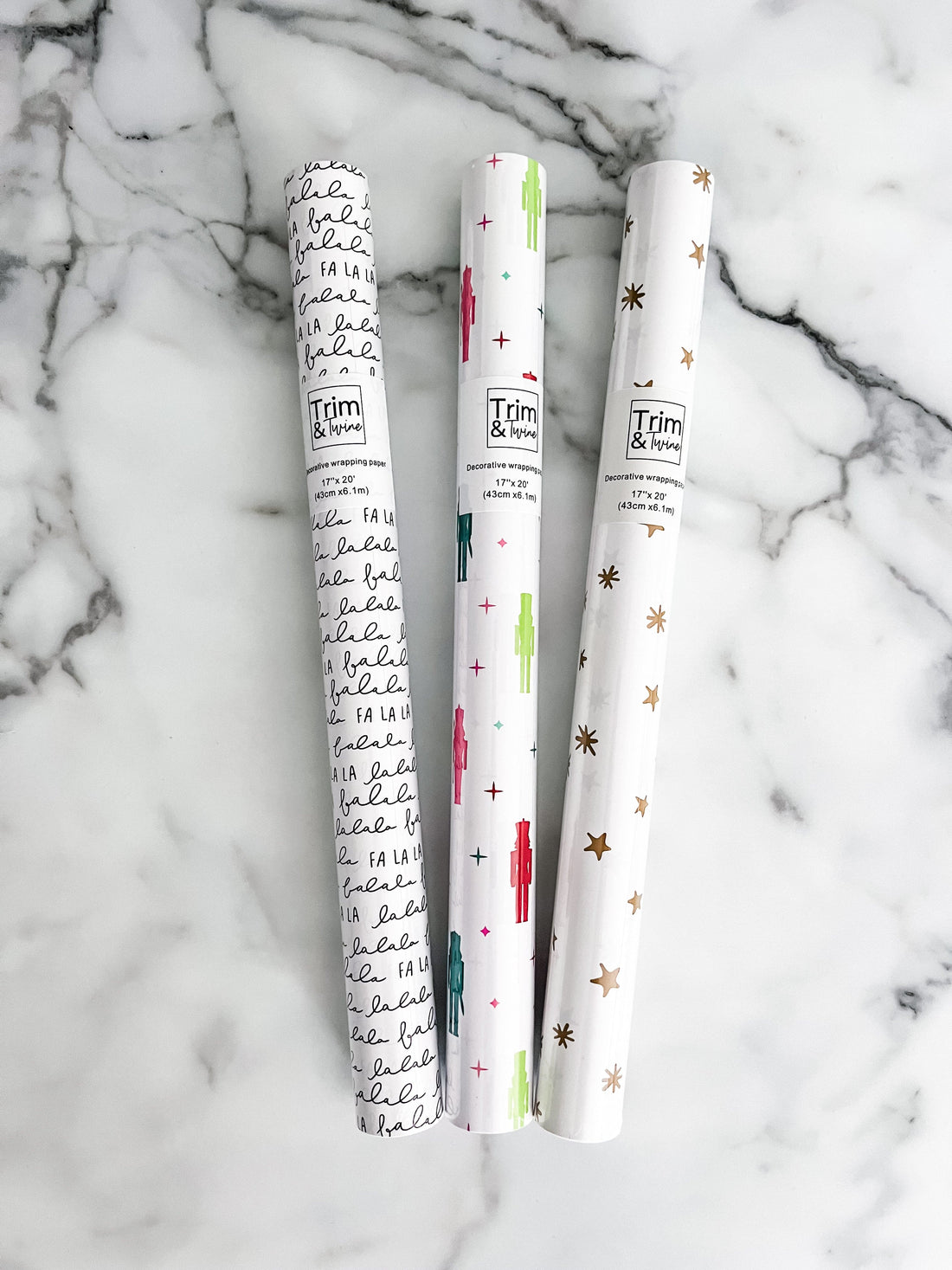 Three rolls of decorative paper with different designs on a marble surface