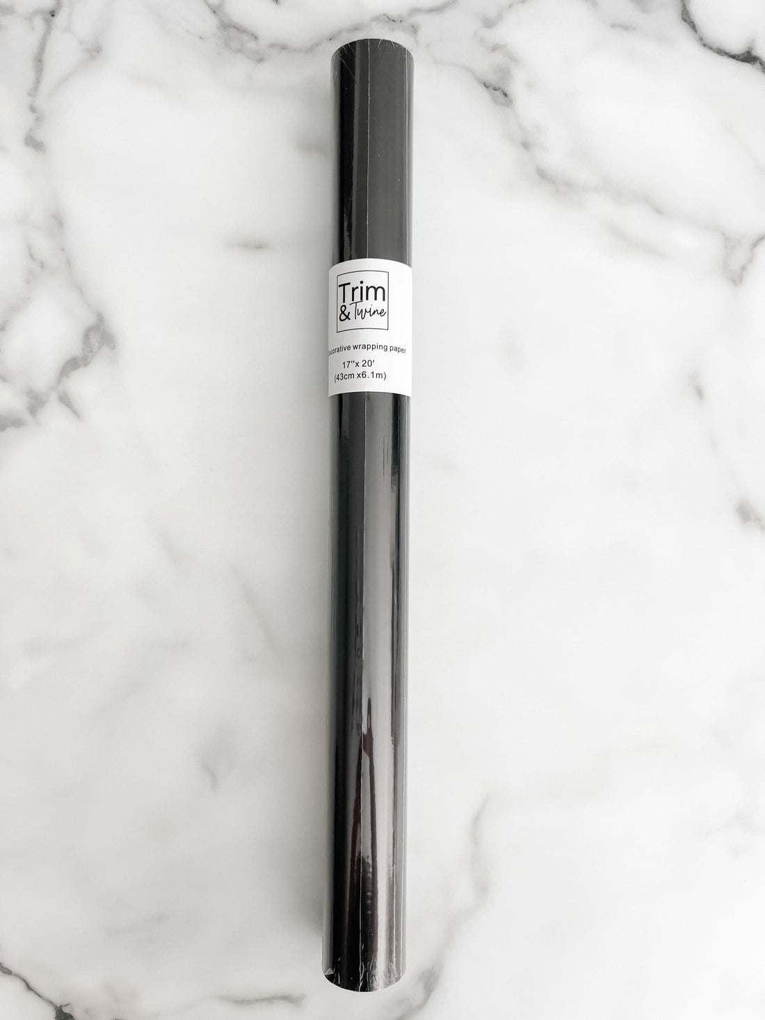 A roll of solid black wrapping paper with a label in the middle, placed on a marble surface.