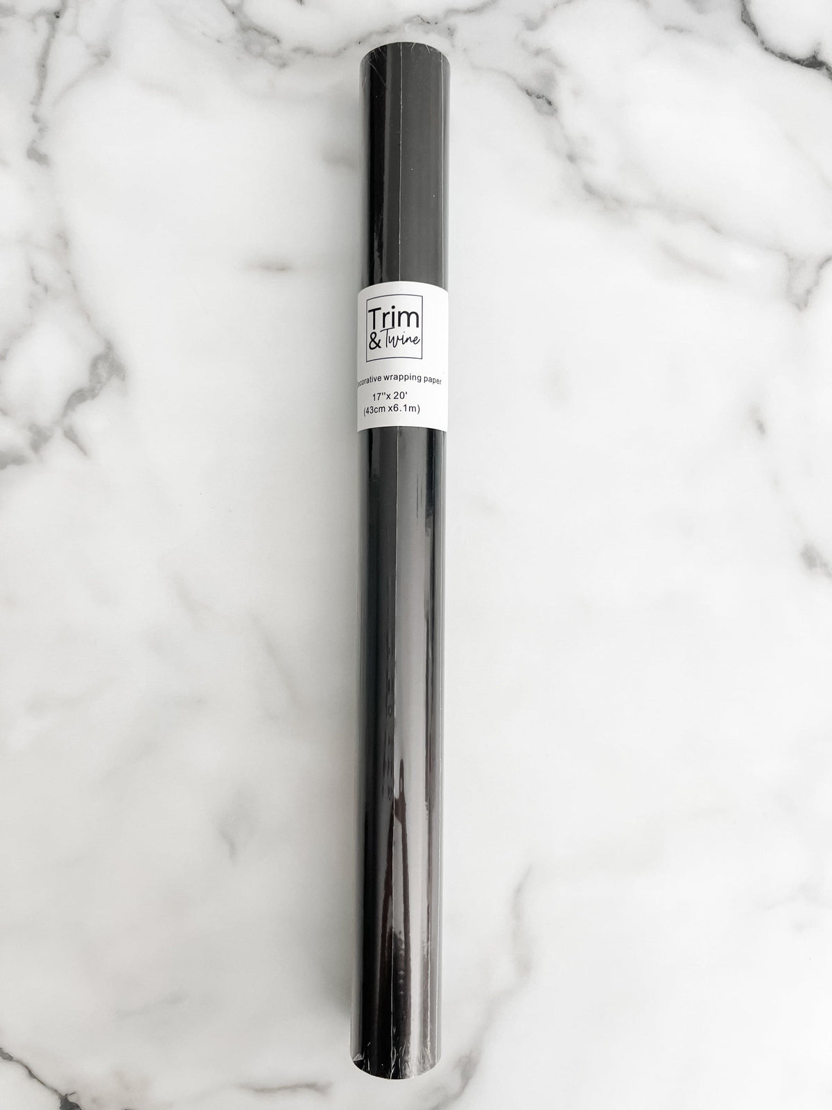 A roll of solid black wrapping paper with a label in the middle, placed on a marble surface.