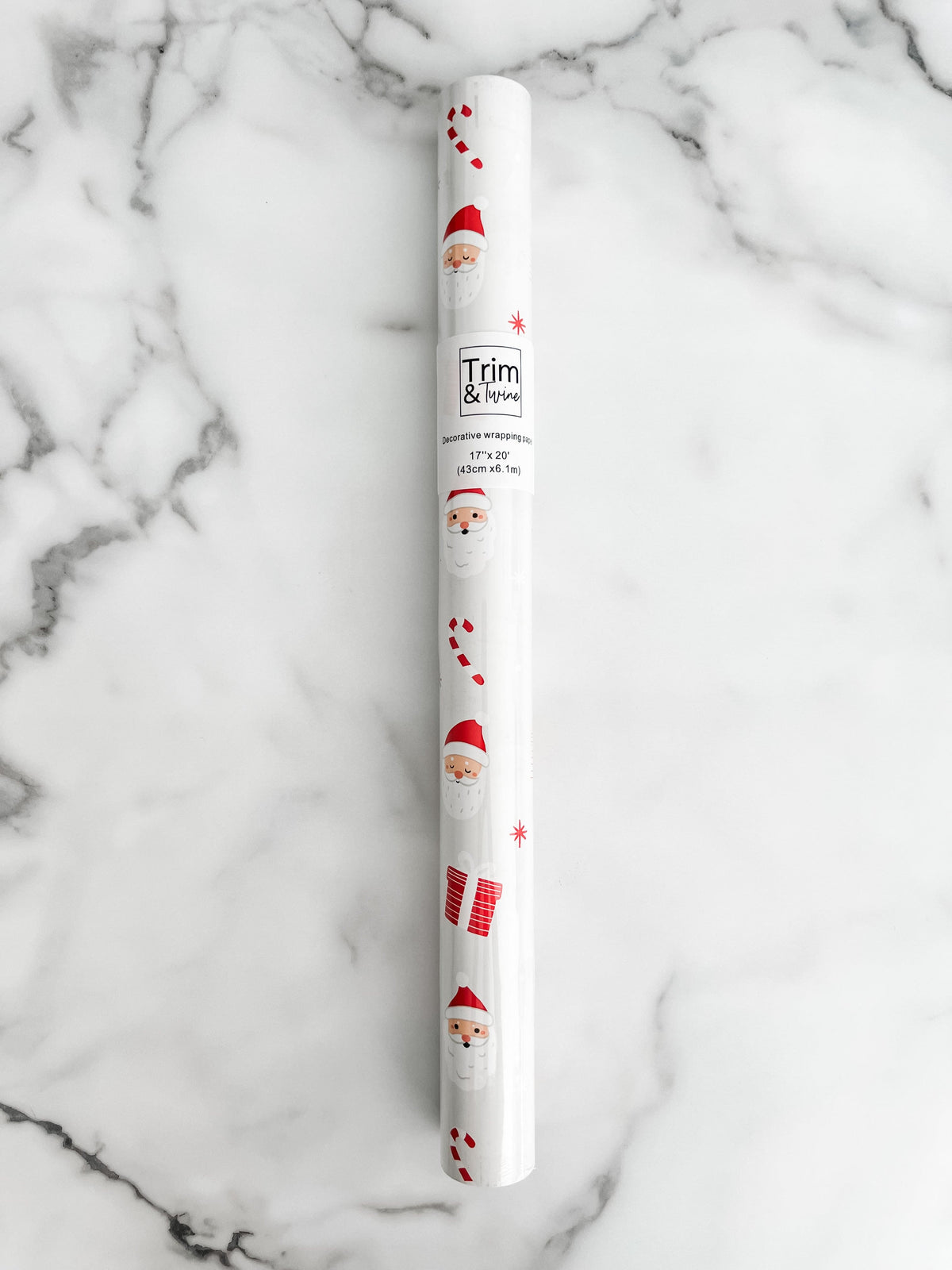 Roll of wrapping paper with a Christmas theme, featuring illustrations of Santa Claus and holiday motifs in red and white colors.