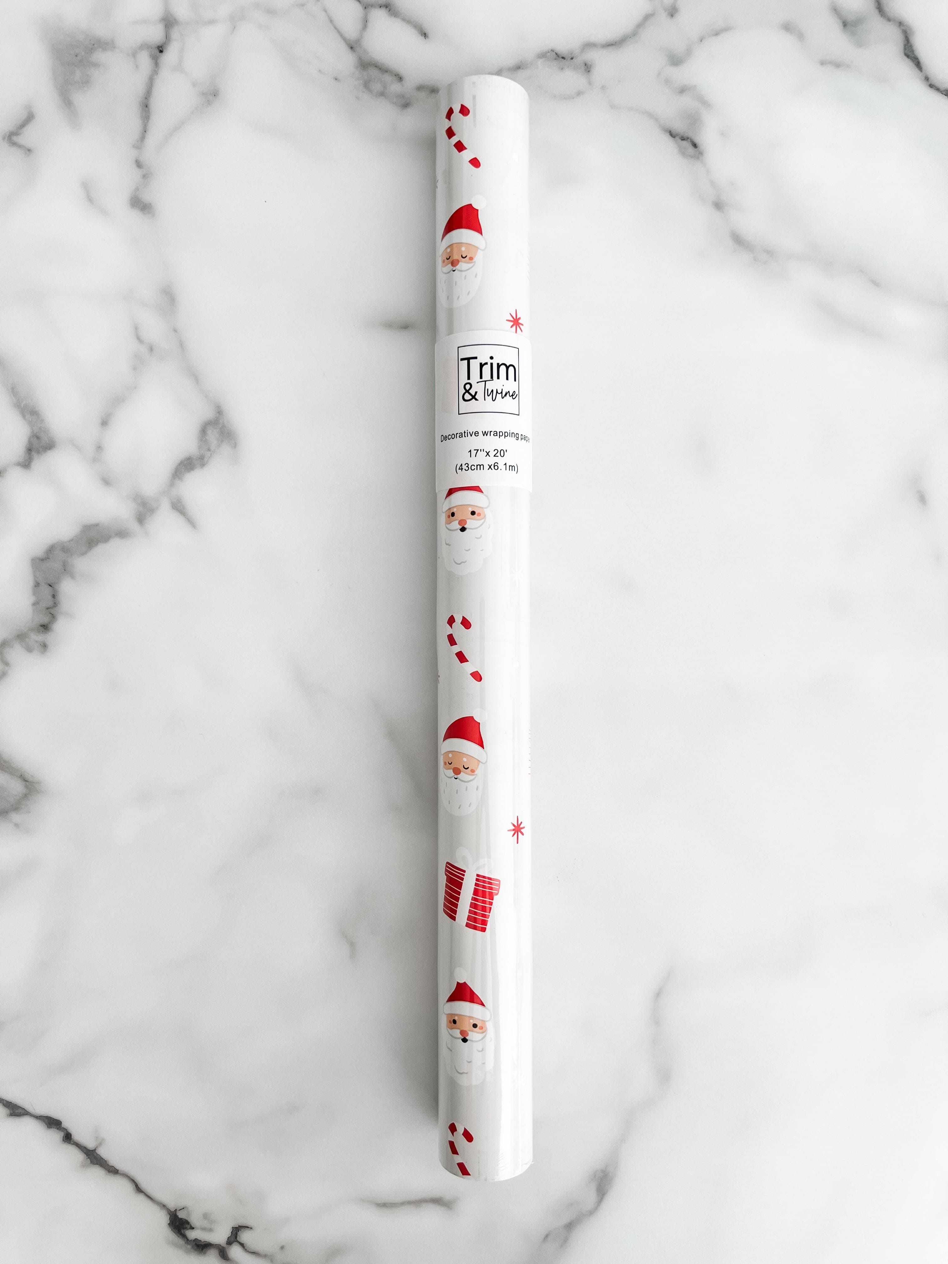 Roll of wrapping paper with a Christmas theme, featuring illustrations of Santa Claus and holiday motifs in red and white colors.
