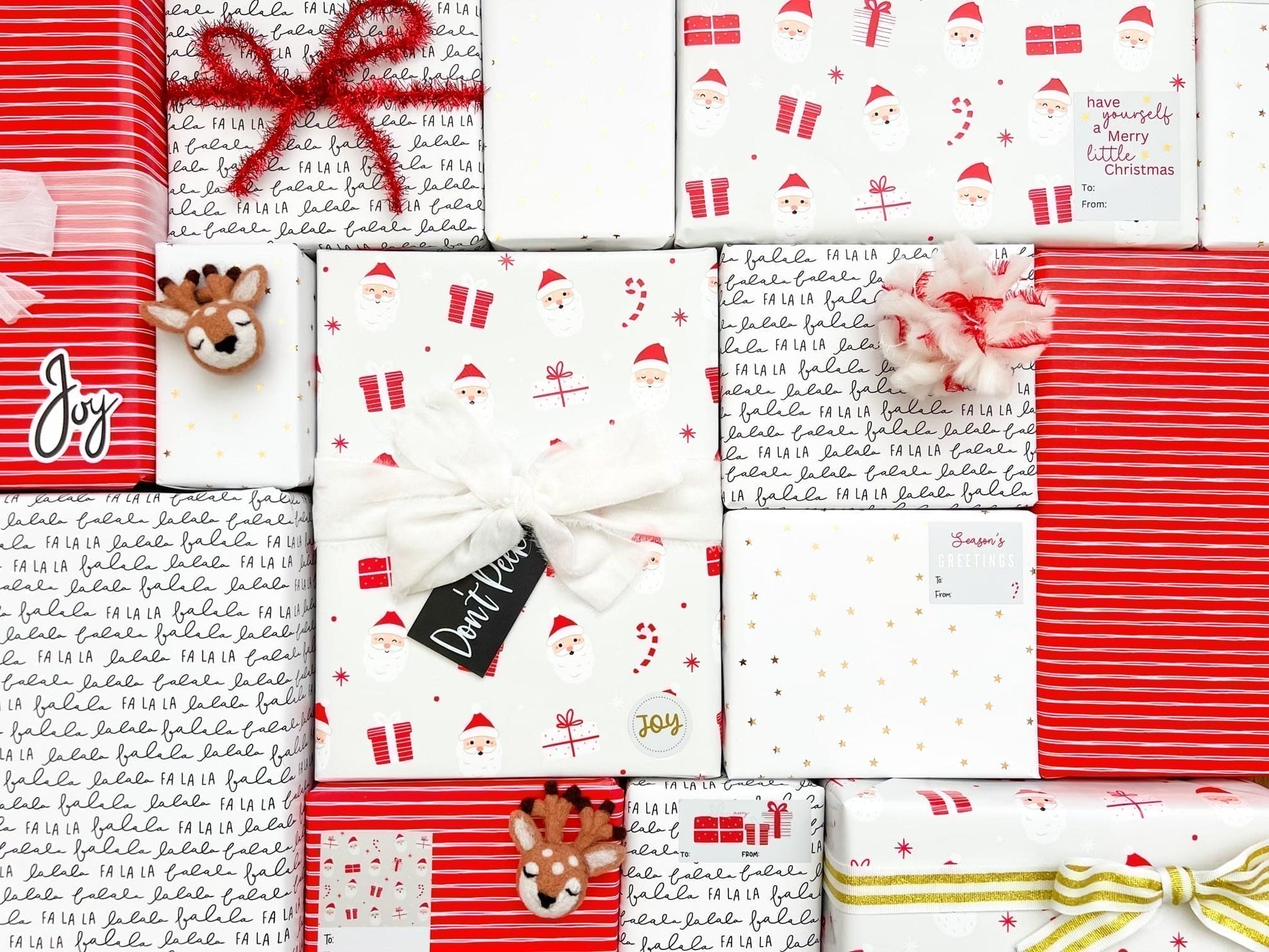 A flat-lay arrangement of Christmas-themed wrapping paper sheets and gift boxes.
