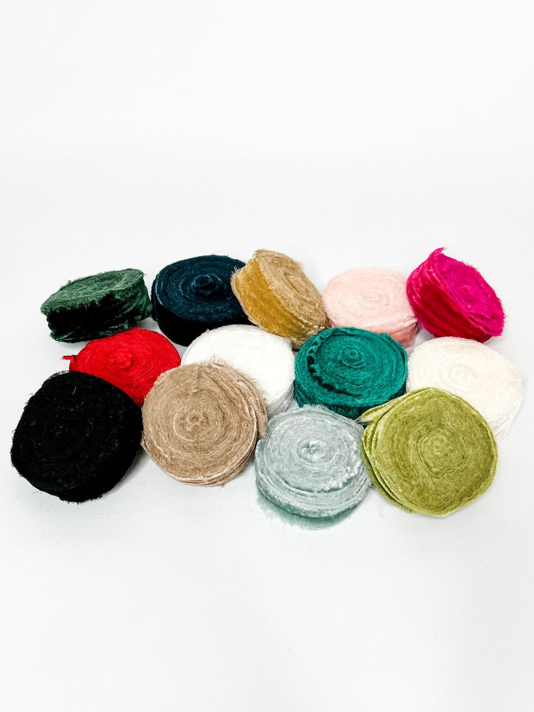 A collection of velvet ribbons in various colors including red, green, blue, pink, beige, black, and tan, with raw edges.